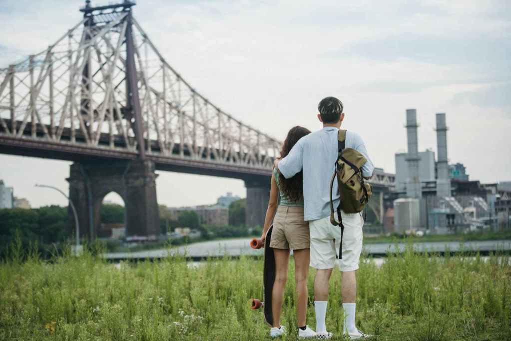 anonymous romantic couple standing near bridge and enjoying cityscape